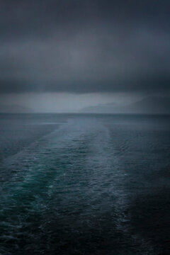 Boat wake behind San Juan Islands ferry on a stormy day with black clouds.