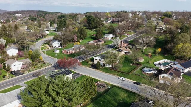 Quiet suburban neighborhood in Akron, Pennsylvania, United States, with residential homes, tree lined streets, and fresh spring colors. Peaceful small town atmosphere under soft daylight. Aerial view.