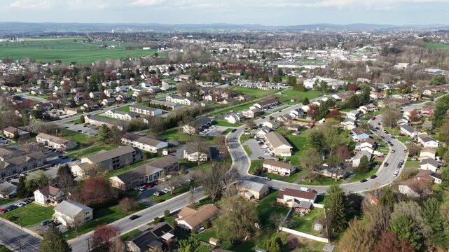 Aerial sunny view of Akron,PA neighborhood in Lancaster County with quiet residential streets, homes and spring trees. Drone shot of peaceful small town community with suburban landscape in USA.