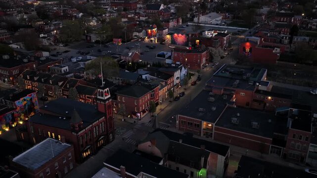 Aerial view of downtown York, Pennsylvania at dusk with historic brick buildings, illuminated streets and landmark tower with American flag. Scenic evening city center scene in USA.