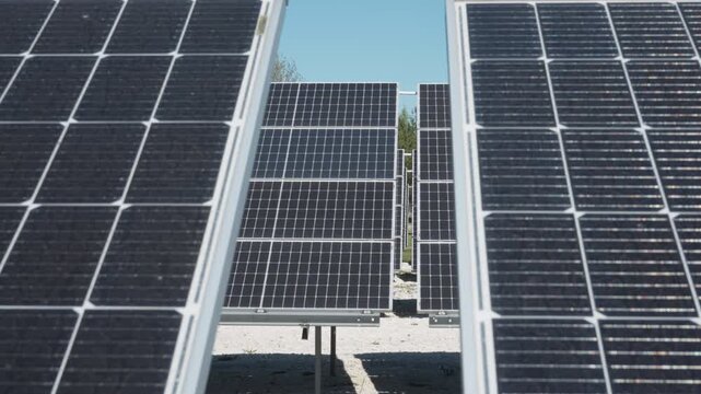 Bifacial photovoltaic solar panels array at industrial renewable energy farm. Ground mount module installation on white gravel for high albedo effect and power generation yield outdoors.