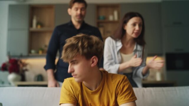Unhappy teen boy listening to annoyed parents scolding him, emotional stress
