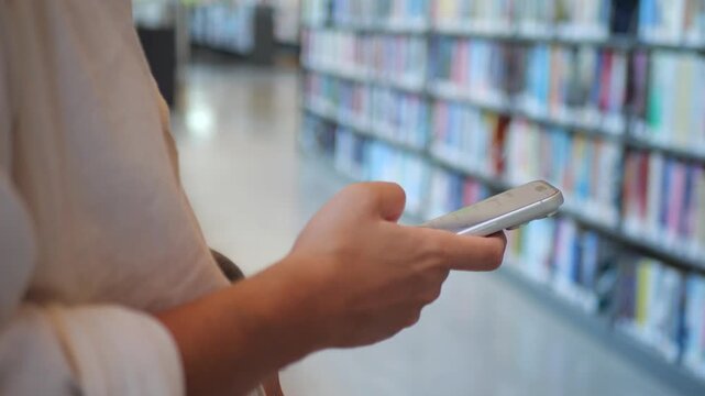 Close-Up of Person Using Smartphone In Library, Representing Modern Mobile Technology, Digital Connectivity, and Online Communication