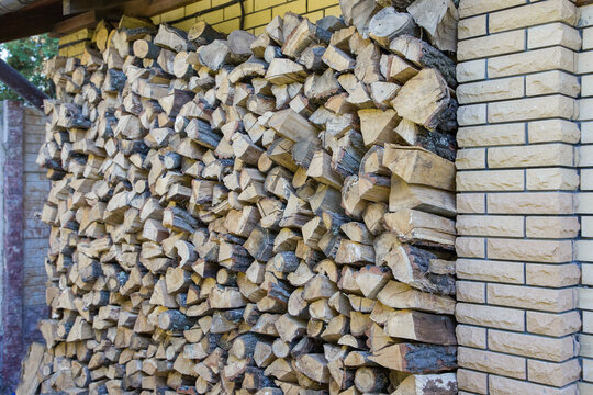Firewood stacked in a pile on a background of a brick wal