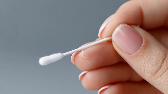 Woman with a french manicure holding a sterile cotton swab for hygiene and beauty care procedures