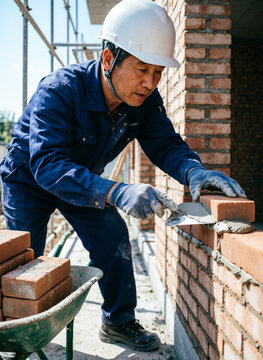 construction worker  laying red bricks to build a sturdy wall