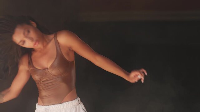 Slim African American female heel dancer performing sensual hip hop on stage