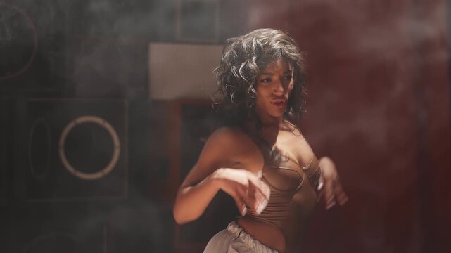 African American woman dancing confidently on stage during music video shoot