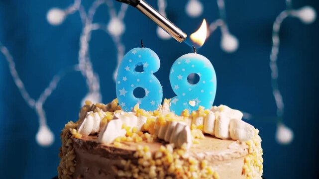 Birthday cake with a 69 number candle placed on a blue background captured in slow motion and close-up view shows an elegant and memorable celebration moment. 