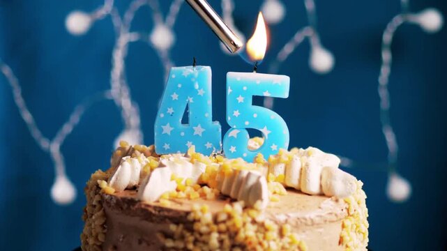 Birthday cake with a 45 number candle placed on a blue background captured in slow motion and close-up view shows a warm and elegant milestone celebration. 