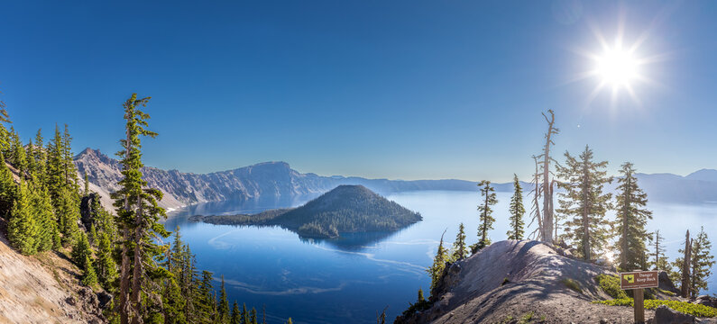 Deep blue Crater Lake surrounded by steep volcanic caldera cliffs with Wizard Island under a clear Oregon sky