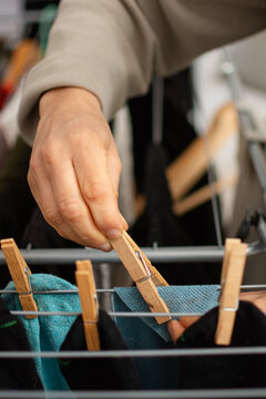 Detail of hand clipping kitchen towel with clothespin on drying rack
