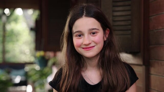 Girl aged 11 smiling and looking at camera in a garden outdoor lifestyle portrait with natural light