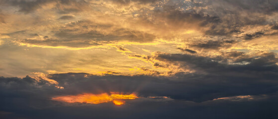 Obraz premium Golden Sunset Light Behind Dark Evening Clouds