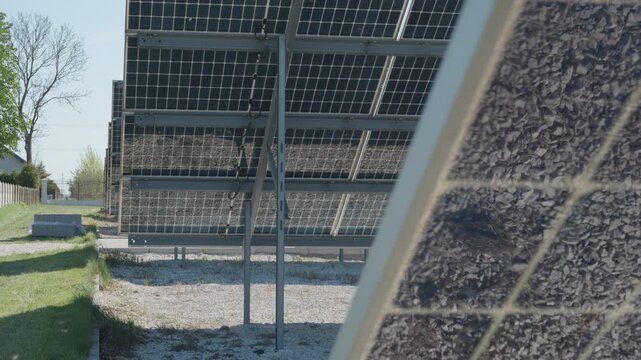 Rear view of bifacial photovoltaic solar panels installed on metal racking. White gravel surface used for albedo effect to increase energy yield on industrial renewable power plant farm.