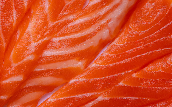 Close-up texture of fresh raw salmon fillet with white fat lines,Macro shot of fresh raw salmon fillet showing detailed texture, vibrant orange color, and natural white marbling fat lines.