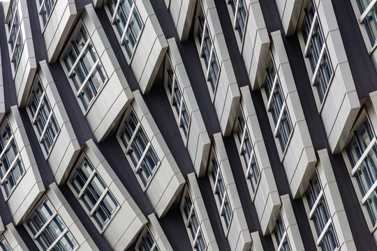 View of the modern facade of The Wave building featuring a repetitive geometric pattern of white panels and windows in Almere, Flevoland, Netherlands.