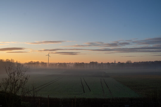 Nebel kroch zwischen die Baumreihen, als w&uuml;rde die Landschaft noch tr&auml;umen, w&auml;hrend das Windrad geduldig seine Kreise zog. Von unserer Terrasse aus sah es aus, als h&auml;tte der Himmel beschlossen, alle G