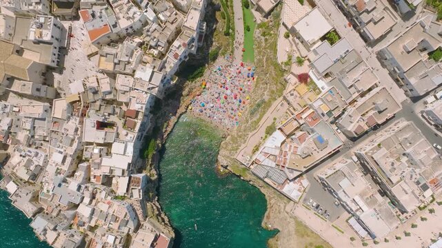 Aerial drone view of Polignano a Mare town in Puglia, Italy. Scenic coastal architecture, historic buildings, and beach by the Mediterranean sea during summer vacation.