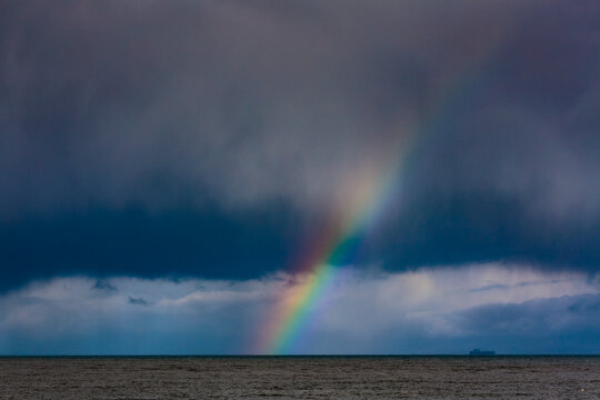 Container ship and Rainbow over water with dark storm clouds on the Strait of Juan de Fuca, Port Angeles