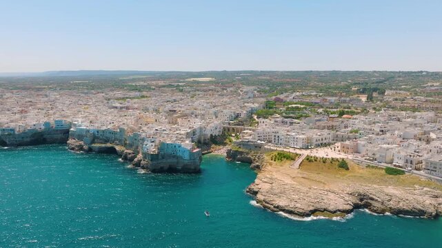 Aerial drone view of Polignano a Mare town in Puglia, Italy. Scenic coastal architecture, historic buildings, and beach by the Mediterranean sea during summer vacation.