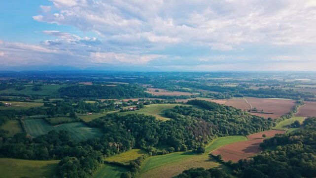 aerial view high above France reveals a stunning patchwork of lush wheat fields and rolling hills in a serene natural setting