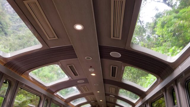 Interior low angle shot of the panoramic glass ceiling on the Vistadome train to Machu Picchu, Peru. Travelers enjoy views of the lush jungle canopy and mountains through the skylight windows