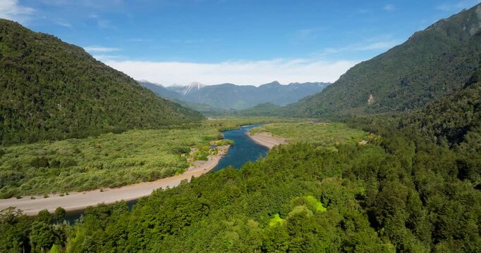 Petrohu&eacute; River flowing through lush green valley in Vicente P&eacute;rez Rosales National Park, Patagonia, Chile. Aerial forward, panoramic view, copy space