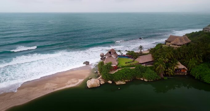 Resorts on Piedras River near scenic sandy Los Naranjos beach in Colombia. Drone