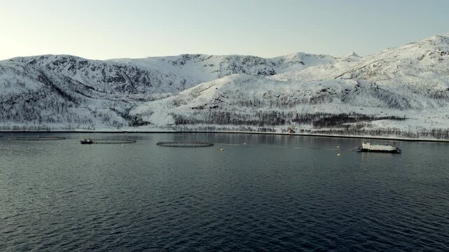 Aerial view over salmon farm with snowy mountains in winter on fjord, Norway