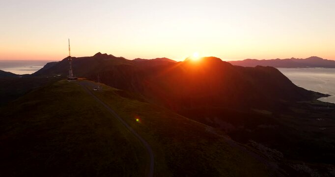 TV and radio tower on top of Storheia mountain during beautiful midnight sun sunset in Hadsel, Norway. Aerial backward