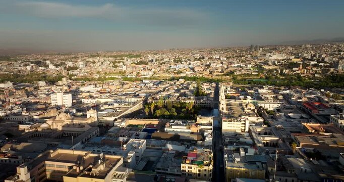 Drone captures the sunrise over the historic white city center and cathedral in Arequipa, Peru, featuring colonial architecture and mountains