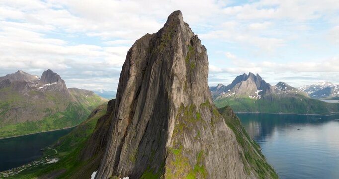 Sharp peak of Segla mountain on Senja island, with fjords in background in Norway. Aerial forward