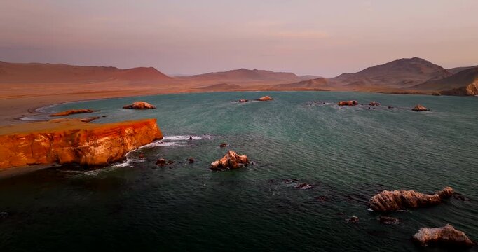 Stunning landscape where desert meets ocean in Paracas National Reserve during golden hour in Peru. Aerial forward, copy space