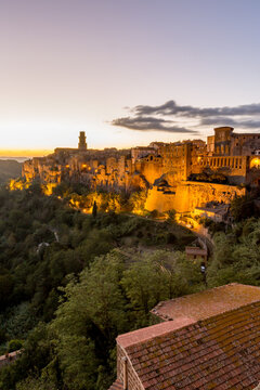 Trees are in the foreground of a city with a castle in the background, Sovana, Tuscany, Italy, long exposure motion blur