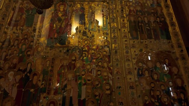 Detailed view of richly decorated golden icons and murals depicting saints and religious figures inside the Holy Trinity Cathedral in Tbilisi, Georgia. Ornate craftsmanship with spiritual significa...