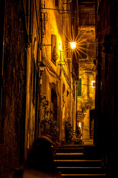 Diffraction view of street at night with person walking down the street, Sovana, Tuscany, Italy, long exposure motion blur