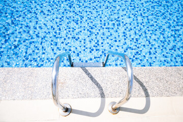 Swimming pool ladder with clear blue water and mosaic tiles © Bauyrzhan