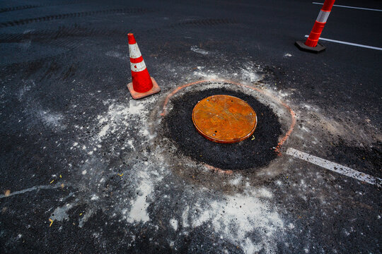 Road construction over sewer manhole cov, WA USA