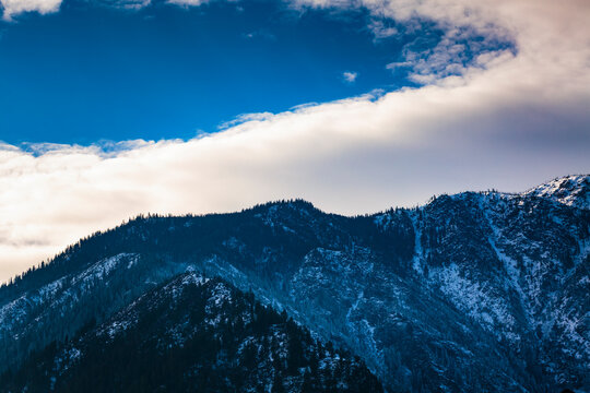 Cascade Mountains rising above Leavenworth, low cloud and a blue sky patch.