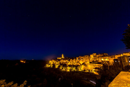 Nighttime view of a town with a clock tower and street light, Sovana, Tuscany, Italy, long exposure motion blur
