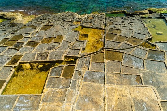 Empty salt pans carved into the coastal limestone rock formations along the shoreline of eastern Malta near Marsaskala.  