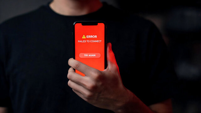 Close-up shot of a frustrated person holding a smartphone displaying an error message, featuring a dark moody background and dramatic lighting.