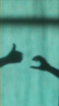 Silhouette hand gesture behind textured glass, abstract approval and friendzone concept, symbolic communication idea.
