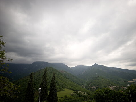Paesaggio montano con colline ricoperte da vegetazione fitta, profondit&agrave; naturale tra i vari rilievi e cielo nuvoloso che crea un&rsquo;atmosfera tranquilla e immersiva