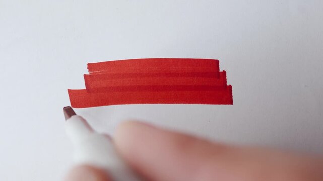 Red marker strokes and hatching cloud with real marker for text overlay on textured white paper close up.