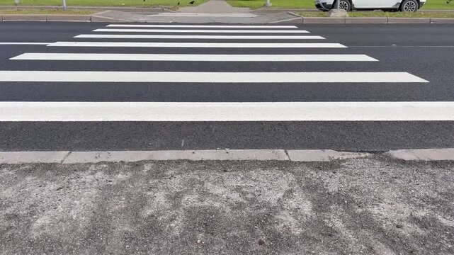 Crosswalk view shows cars approaching while people wait to cross a street