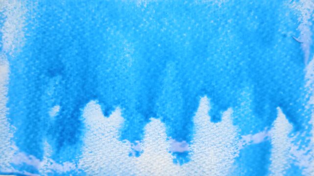 Close up of blue watercolour drawing paints on paper. Artist draws with a brush, liquid analog effects for background with copy space for text in center. 
