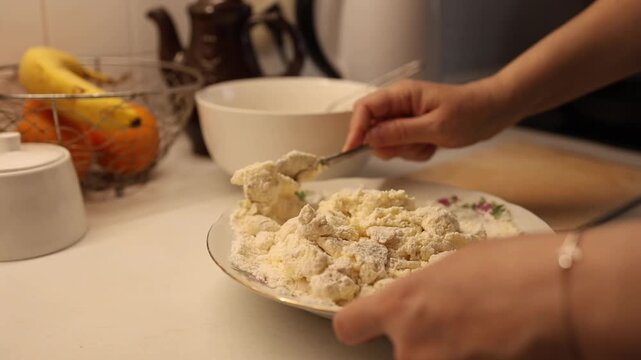 Hands mixing a white creamy substance like cottage cheese or batter in a bowl, preparing ingredients.