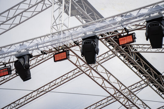 Modern entertainment technology featuring robotic moving head lights and professional stage illumination gear installed on an overhead truss for a public outdoor event
